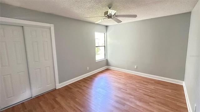 unfurnished bedroom featuring a textured ceiling, a closet, ceiling fan, and hardwood / wood-style flooring