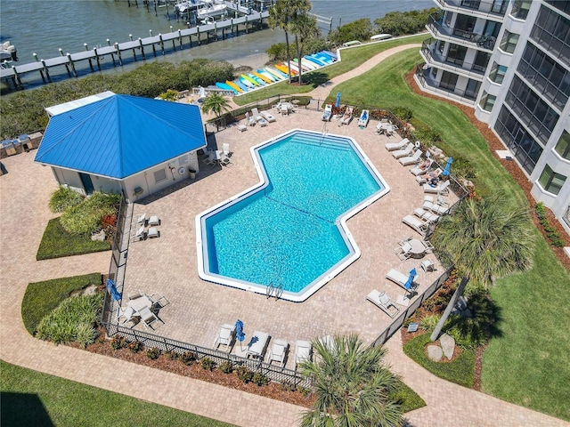 view of pool with a patio, a lawn, and a water view