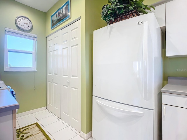 kitchen with white cabinetry, white fridge, and light tile patterned floors