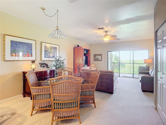 dining room with a textured ceiling, light colored carpet, and ceiling fan