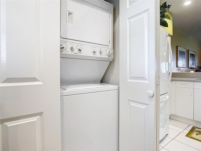 laundry room featuring stacked washer / drying machine and light tile patterned flooring