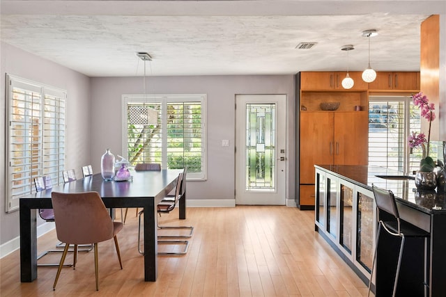 dining space featuring a textured ceiling, light wood-type flooring, and plenty of natural light