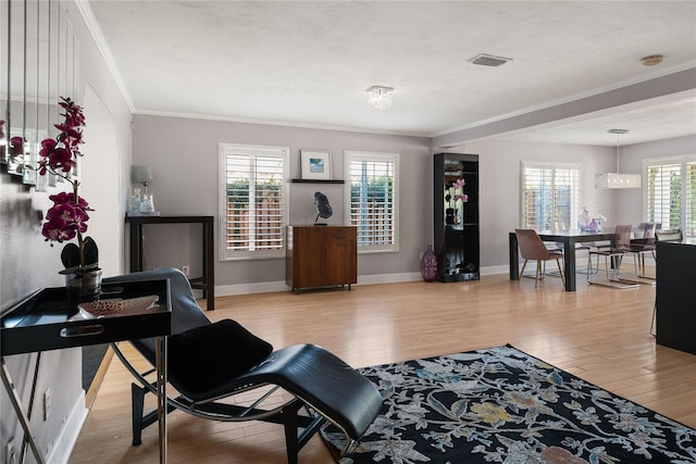 living room with light wood-type flooring, crown molding, and plenty of natural light