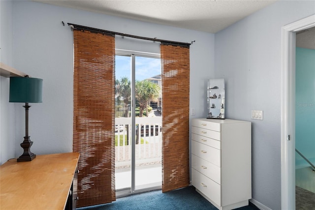 doorway to outside with a textured ceiling and dark colored carpet