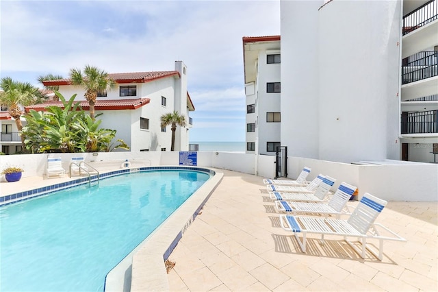 view of pool featuring a patio and a water view