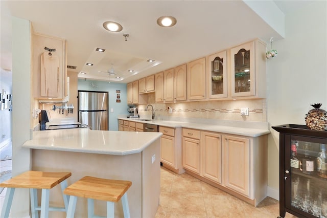 kitchen featuring stainless steel refrigerator, kitchen peninsula, wine cooler, and a breakfast bar