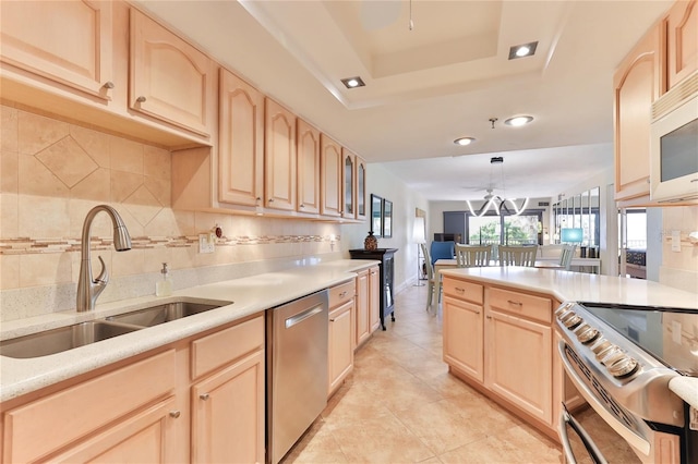 kitchen featuring light brown cabinetry, appliances with stainless steel finishes, hanging light fixtures, and sink