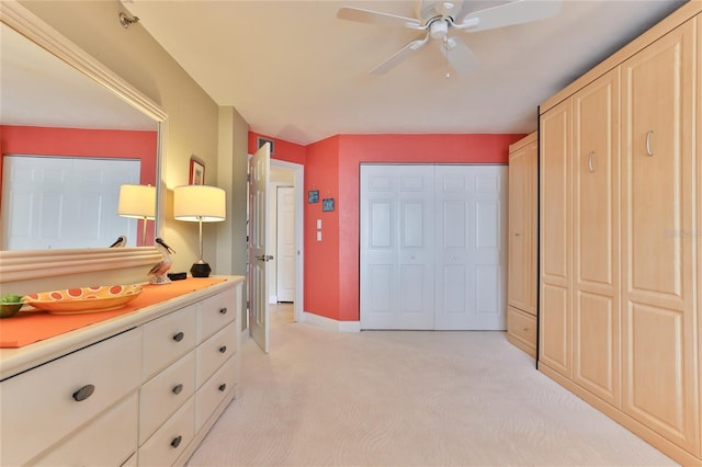 bedroom with ceiling fan, light colored carpet, and two closets