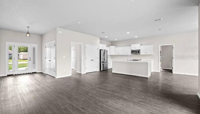 unfurnished living room with dark hardwood / wood-style flooring and a textured ceiling