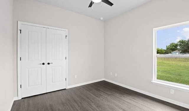 unfurnished bedroom with dark hardwood / wood-style flooring, multiple windows, a closet, and ceiling fan