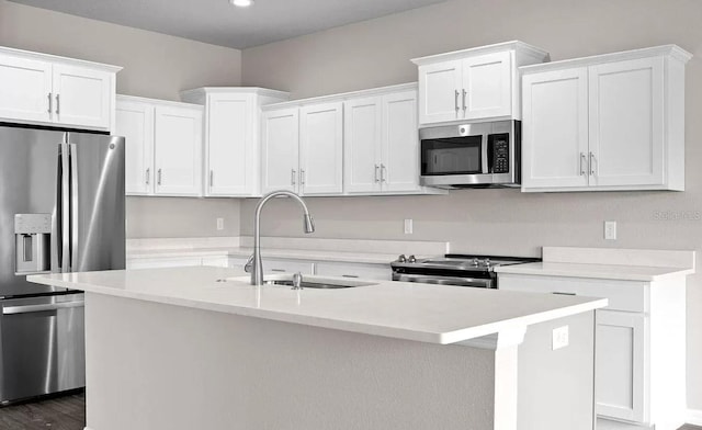 kitchen with sink, white cabinetry, stainless steel appliances, a center island with sink, and dark hardwood / wood-style flooring