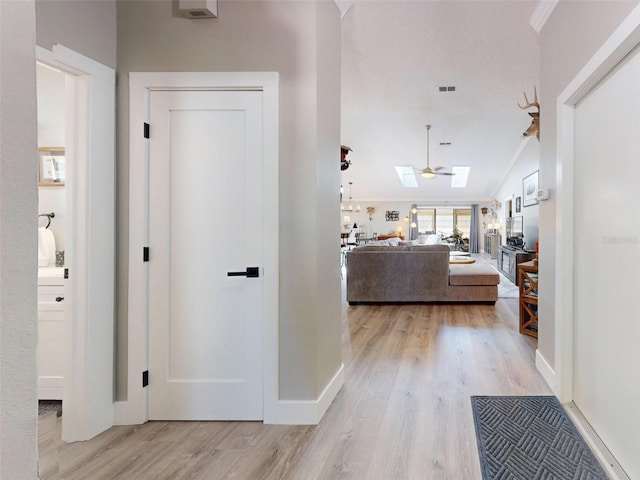 hall featuring a skylight, ornamental molding, and light hardwood / wood-style floors