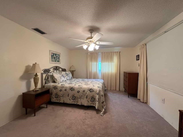 carpeted bedroom with ceiling fan and a textured ceiling