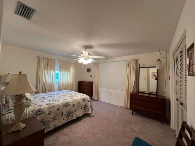 carpeted bedroom featuring a closet, ceiling fan, and a textured ceiling