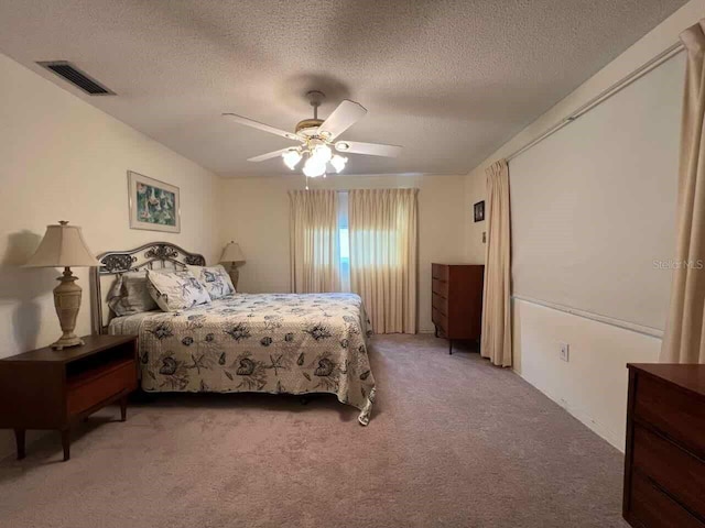 carpeted bedroom featuring a textured ceiling and ceiling fan