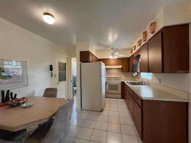 kitchen featuring white fridge, ceiling fan, range, sink, and light tile floors