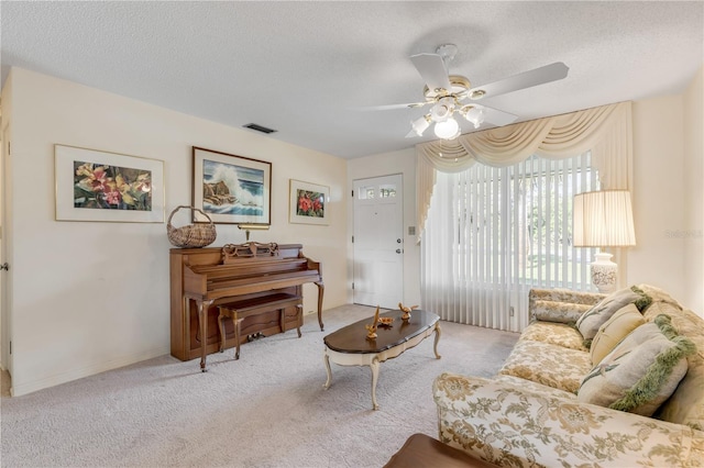 carpeted living room featuring ceiling fan and a textured ceiling