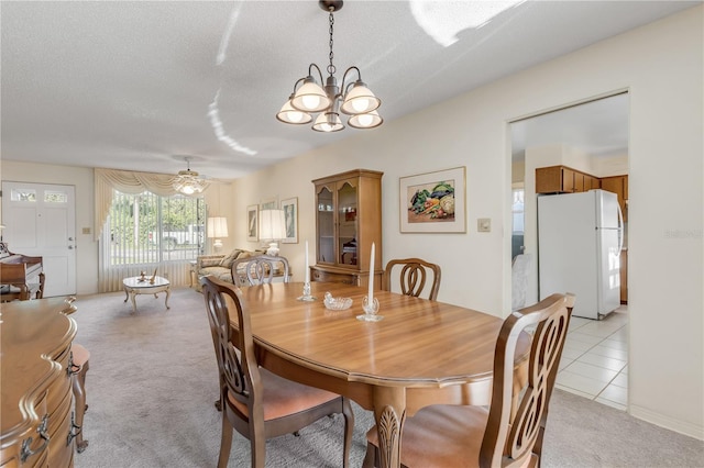 carpeted dining space featuring ceiling fan with notable chandelier and a textured ceiling