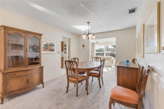 dining area with light colored carpet, a textured ceiling, and an inviting chandelier