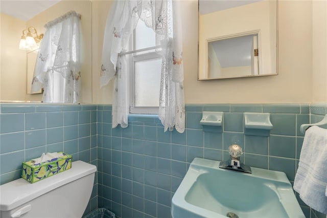 bathroom featuring toilet, tile walls, and sink