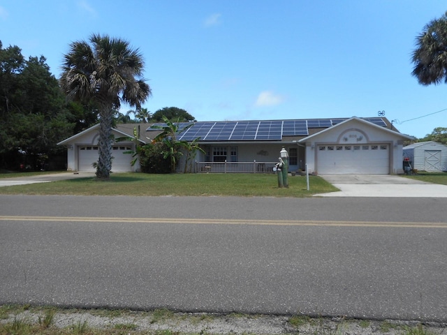 ranch-style house with a garage, a front lawn, and solar panels