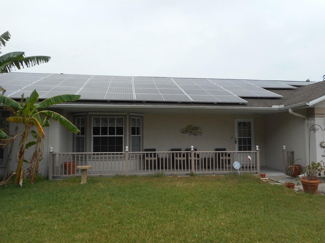 back of house with a lawn and solar panels