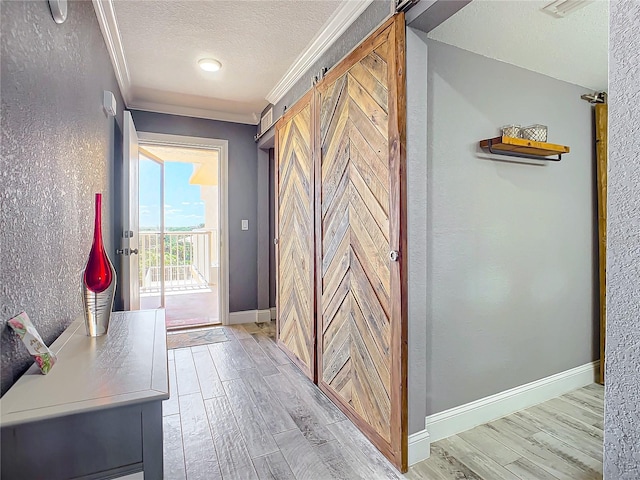 hall featuring ornamental molding, a barn door, and light hardwood / wood-style floors