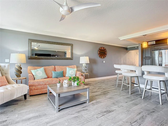 living room featuring ornamental molding, light hardwood / wood-style flooring, ceiling fan, and a textured ceiling