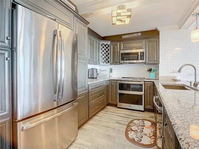 kitchen with sink, light hardwood / wood-style floors, tasteful backsplash, stainless steel appliances, and light stone countertops