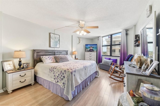 bedroom featuring ceiling fan, light wood-type flooring, and a textured ceiling