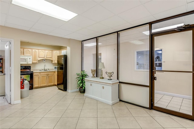 kitchen with black appliances, light tile patterned floors, sink, and light brown cabinetry