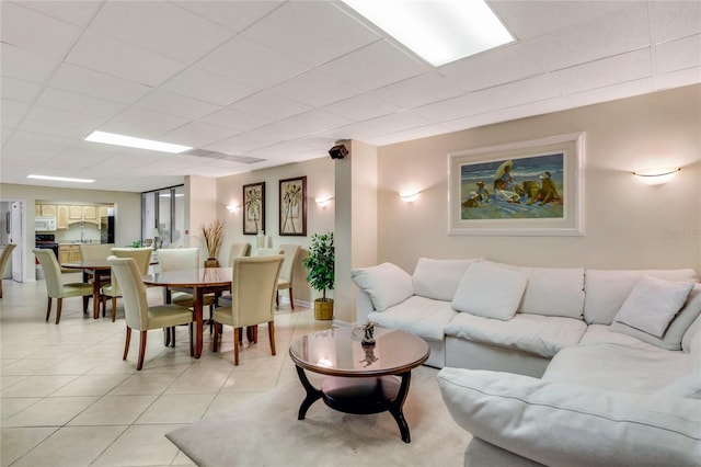 living room with a paneled ceiling and light tile patterned flooring