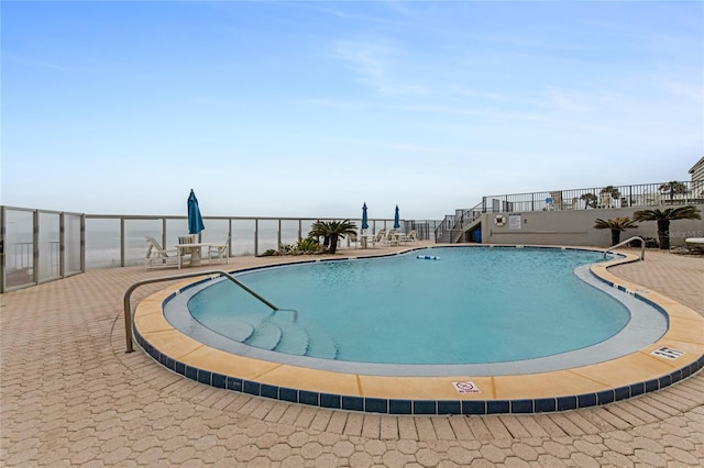 view of swimming pool with a water view and a patio