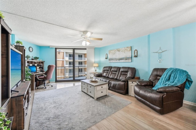 living room with ceiling fan, light hardwood / wood-style flooring, and a textured ceiling