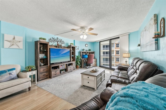 living room with ceiling fan, expansive windows, a textured ceiling, and light hardwood / wood-style flooring