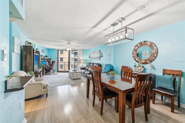 dining space with a textured ceiling, light wood-type flooring, and ceiling fan