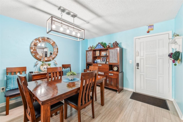 dining area with light wood-type flooring and a textured ceiling