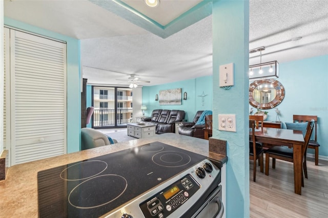 kitchen with electric range, ceiling fan, light hardwood / wood-style floors, and a textured ceiling