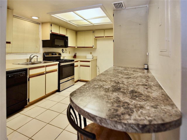 kitchen with sink, cream cabinets, black appliances, and light tile floors