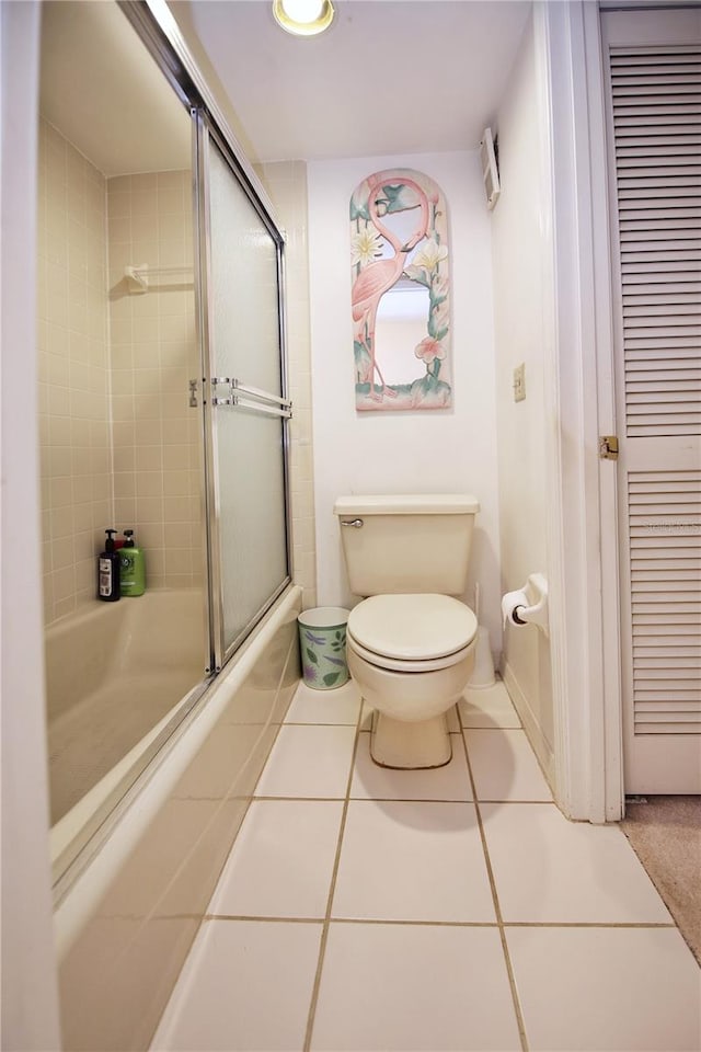 full bath with combined bath / shower with glass door, tile patterned flooring, and toilet