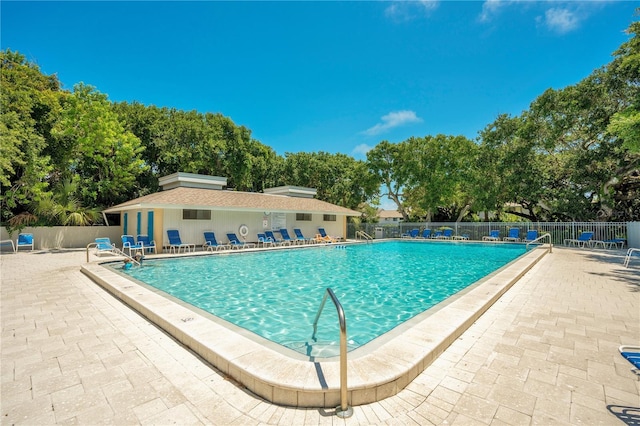 pool with a patio area and fence