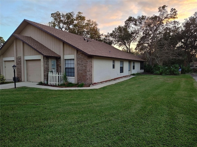 property exterior at dusk with a garage and a yard