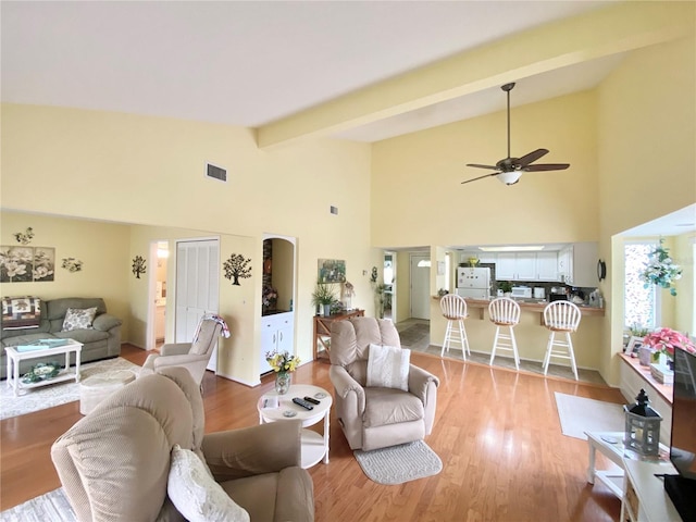 living room featuring ceiling fan, light hardwood / wood-style floors, and vaulted ceiling with beams