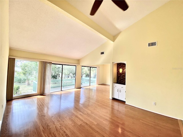 unfurnished living room featuring high vaulted ceiling, beamed ceiling, light wood-type flooring, ceiling fan, and a textured ceiling