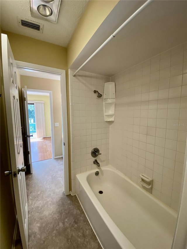 bathroom with tiled shower / bath and a textured ceiling