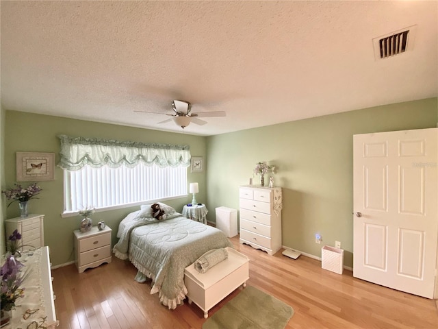 bedroom featuring ceiling fan, light hardwood / wood-style flooring, and a textured ceiling