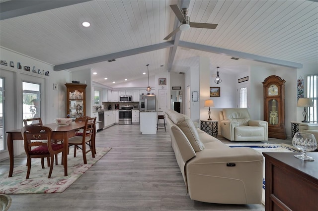 living room with ceiling fan, light hardwood / wood-style flooring, and vaulted ceiling with beams