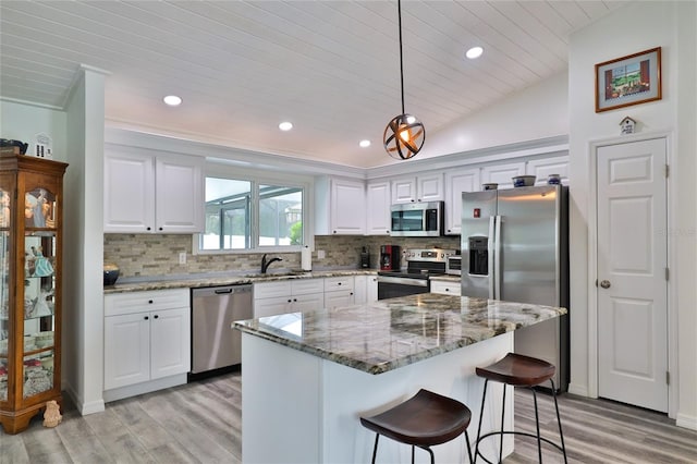 kitchen with stainless steel appliances, pendant lighting, a kitchen island, and white cabinets