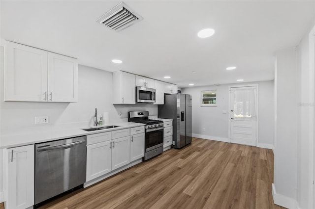 kitchen featuring appliances with stainless steel finishes, light wood-type flooring, and white cabinets