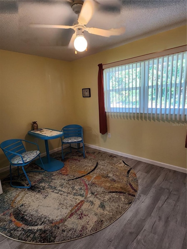 sitting room featuring ceiling fan, a textured ceiling, and wood-type flooring